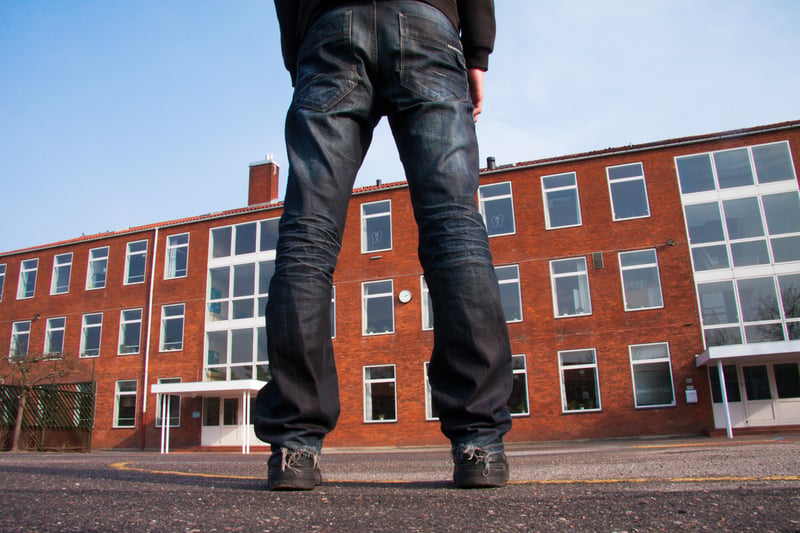 Ung person stående foran en skolebygning