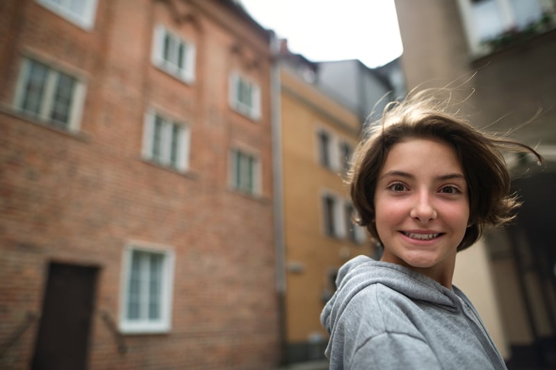 Smilende ung pige der kigger over skulderen i bymiljø