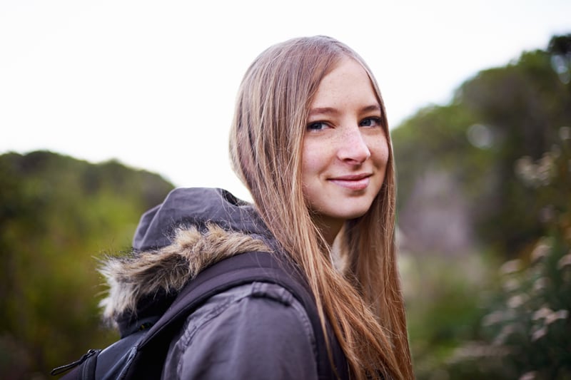 Ung smilende kvinde med lyst hår og vinterjakke udendørs