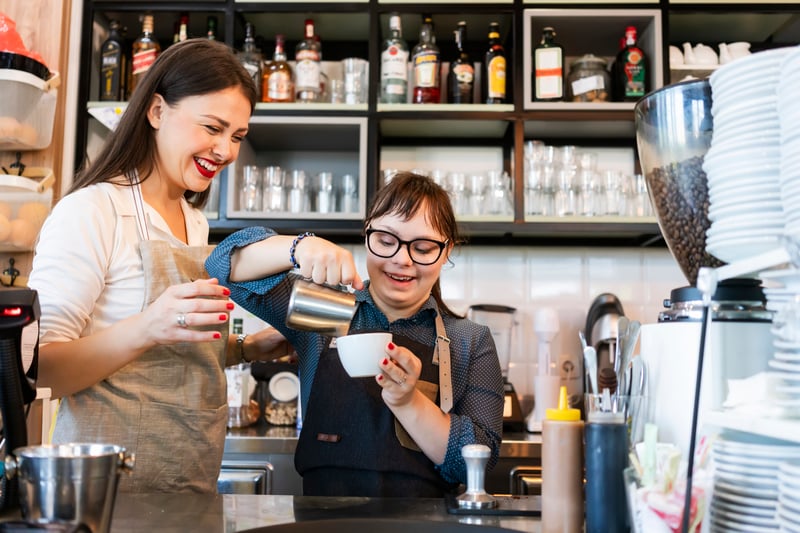To smilende kvinder bag disken i en café i et hjertevarmt samarbejde